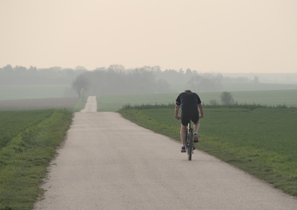 man in black shirt riding bicycle on gray concrete road during daytime
