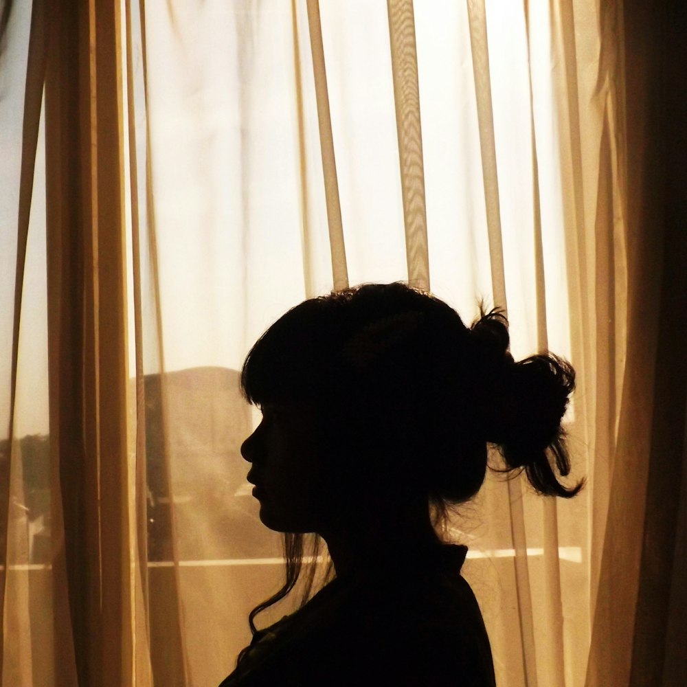 silhouette of woman standing near window