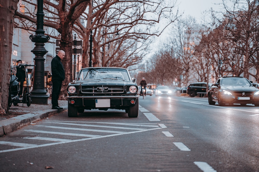 black car on road near bare trees during daytime