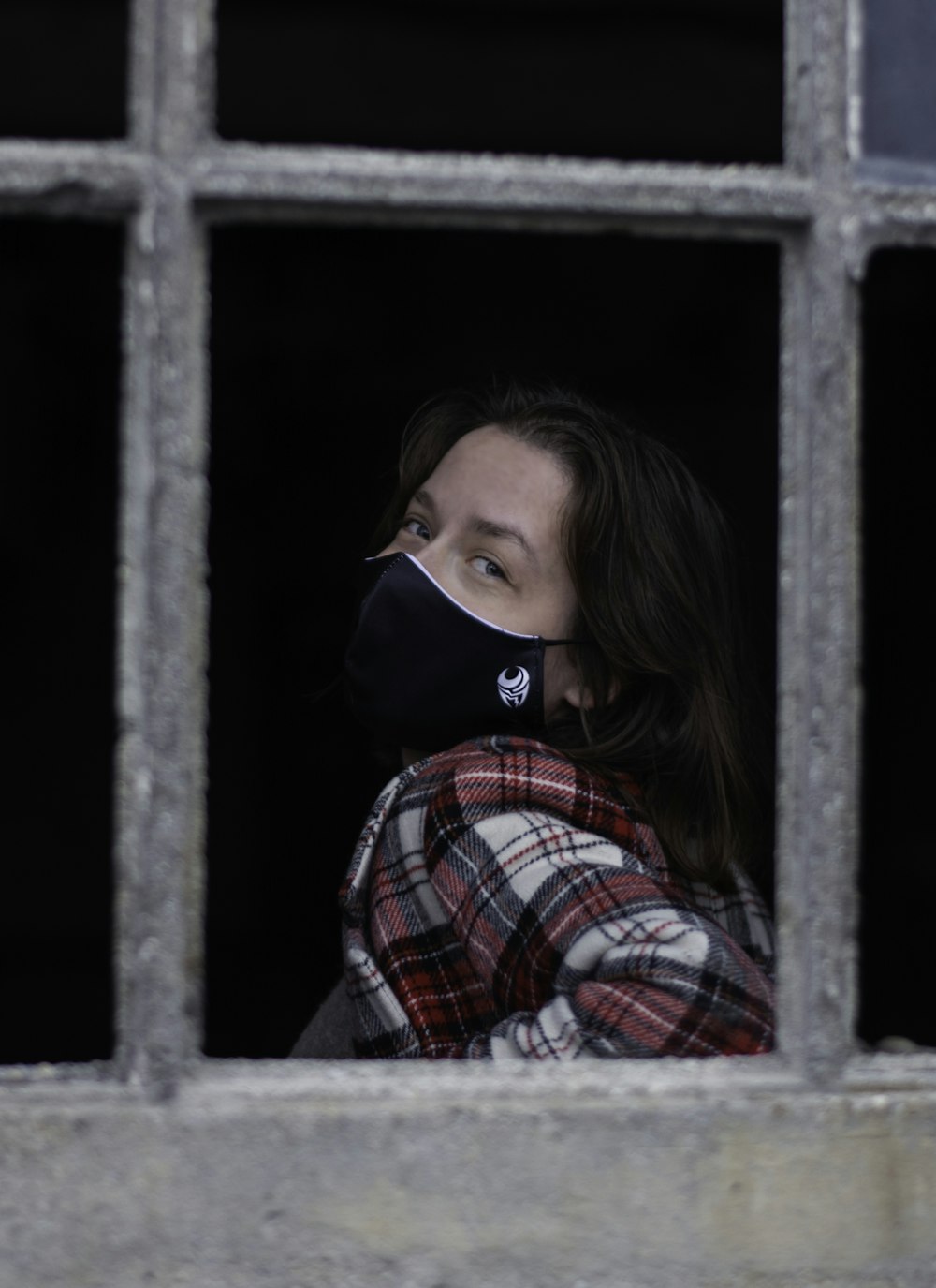 girl in red white and blue plaid dress shirt wearing black and white face mask