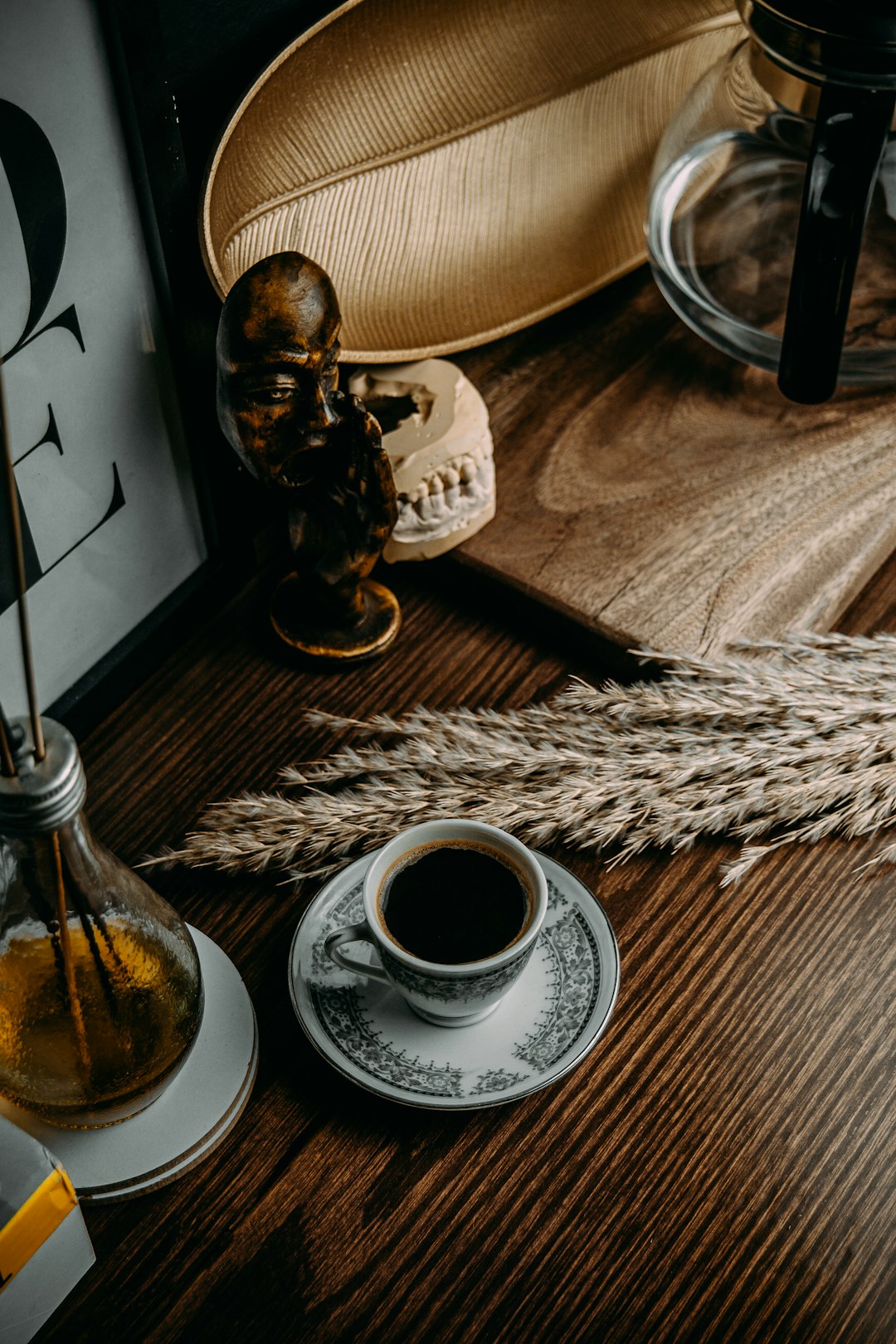 white ceramic cup on saucer beside clear glass bottle