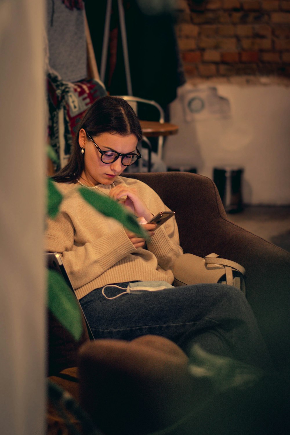 茶色のソファに座る緑のセーターを着た女性