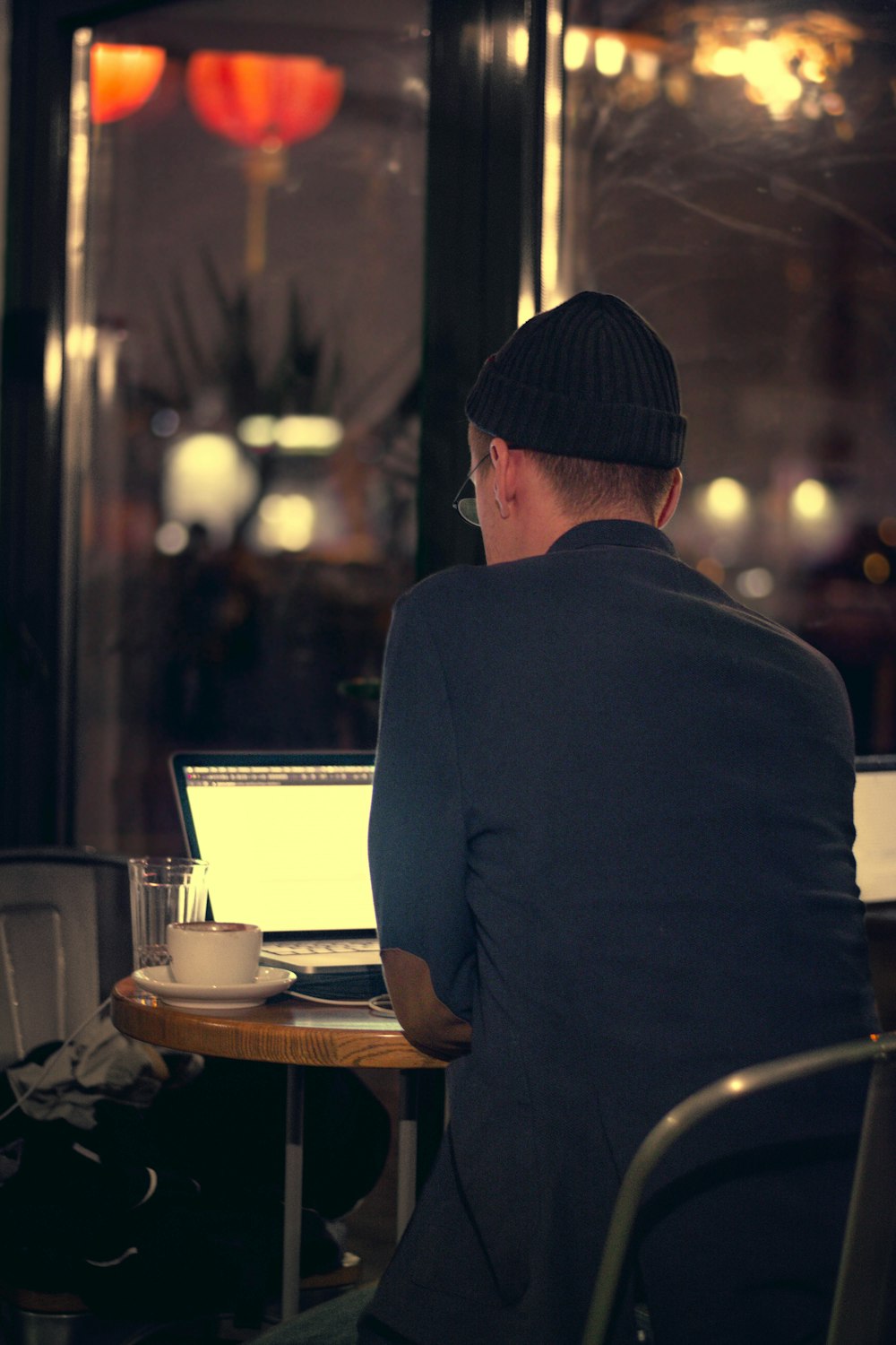 man in black shirt standing in front of table with laptop computer