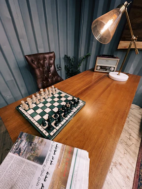A refined desk with elegant Roman-themed stationery beside a vintage chessboard.