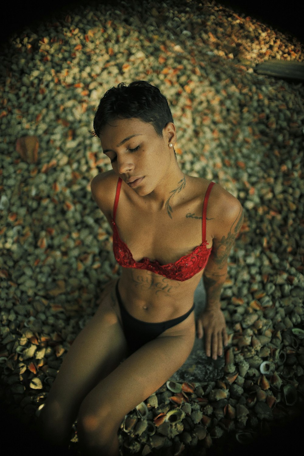 woman in red brassiere and black panty sitting on ground