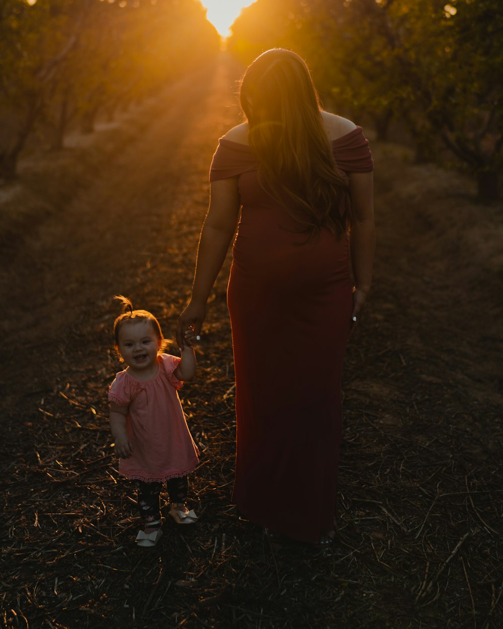 woman in black sleeveless dress holding girl in pink dress