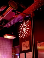 A bold orange neon sign glowing 'stefange: asfalto y grasa' inside a dark, steel-themed workshop