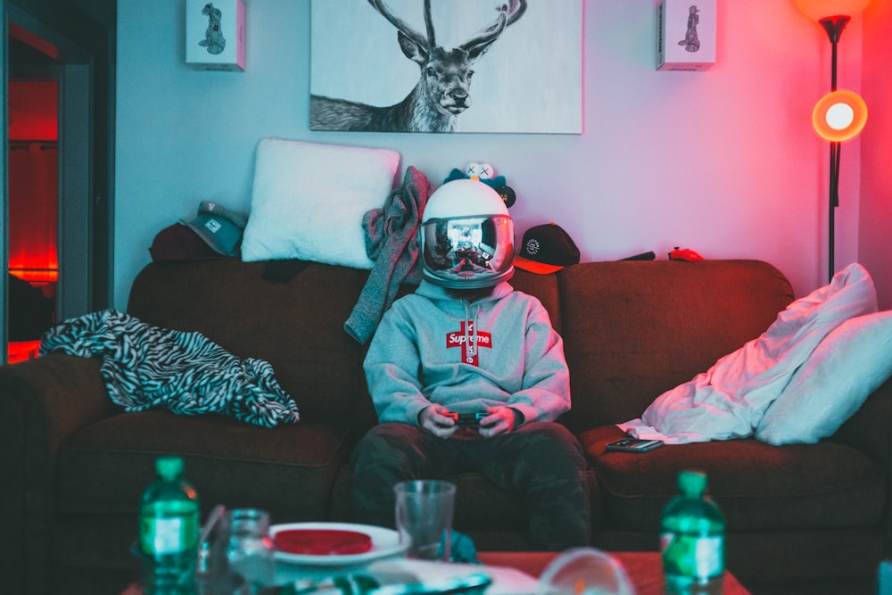 homme en casque rouge et blanc et sweat à capuche rouge assis sur le canapé