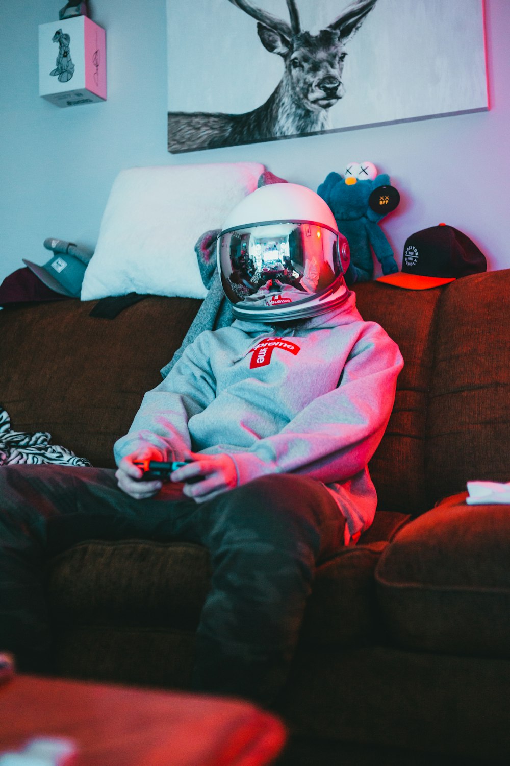 man in pink hoodie wearing helmet sitting on brown couch