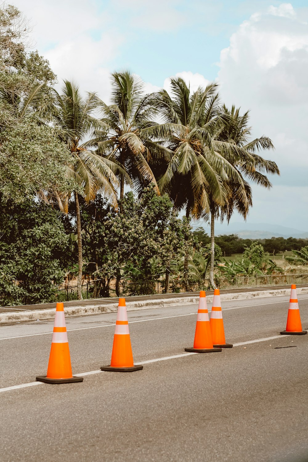 Cône de signalisation orange sur une route asphaltée grise pendant la journée