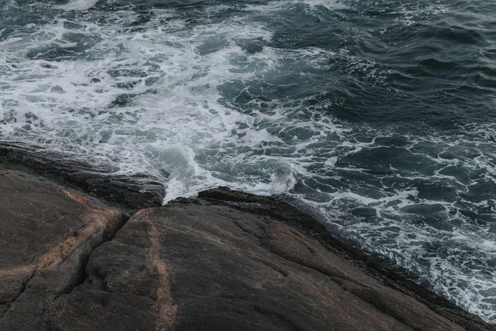 ocean waves crashing on brown rocky shore during daytime