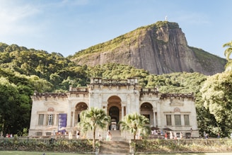 beige concrete building near green mountain under blue sky during daytime
