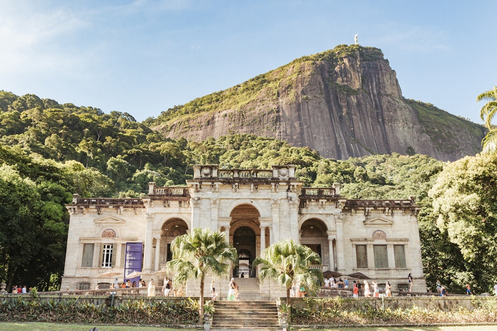 Edificio de hormigón beige cerca de la montaña verde bajo el cielo azul durante el día