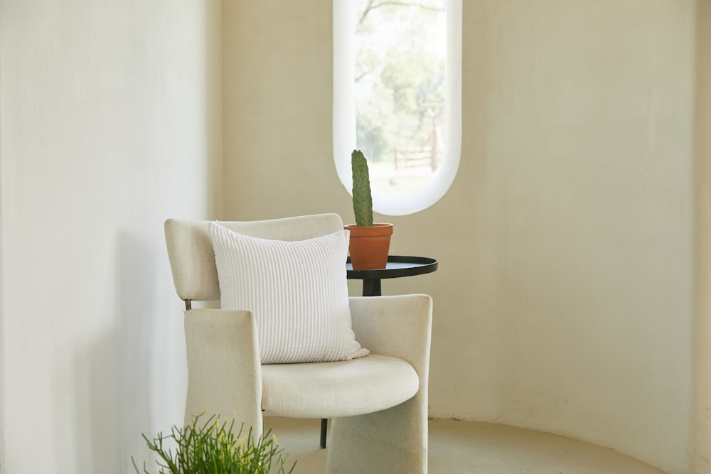 white and gray armchair beside green potted plant