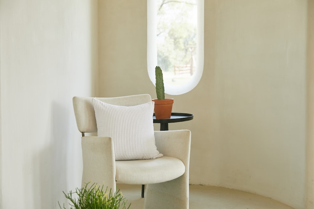 sillón blanco y gris junto a una planta en maceta verde