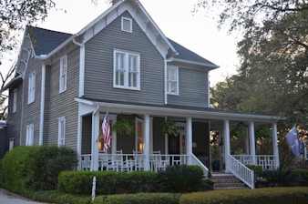 white and gray wooden house near green trees during daytime