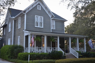 white and gray wooden house near green trees during daytime