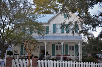A charming two-story house with a white picket fence and garden.