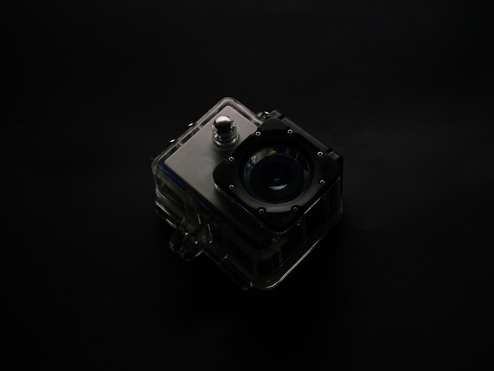 Fotocamera argento e nera su superficie bianca