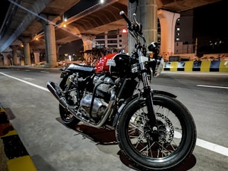 A nighttime shot of a motorcycle parked under streetlights, highlighting the reflective details on riding gear.