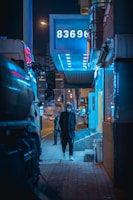 Urban night scene with a person wearing a charcoal hoodie illuminated by neon city lights.