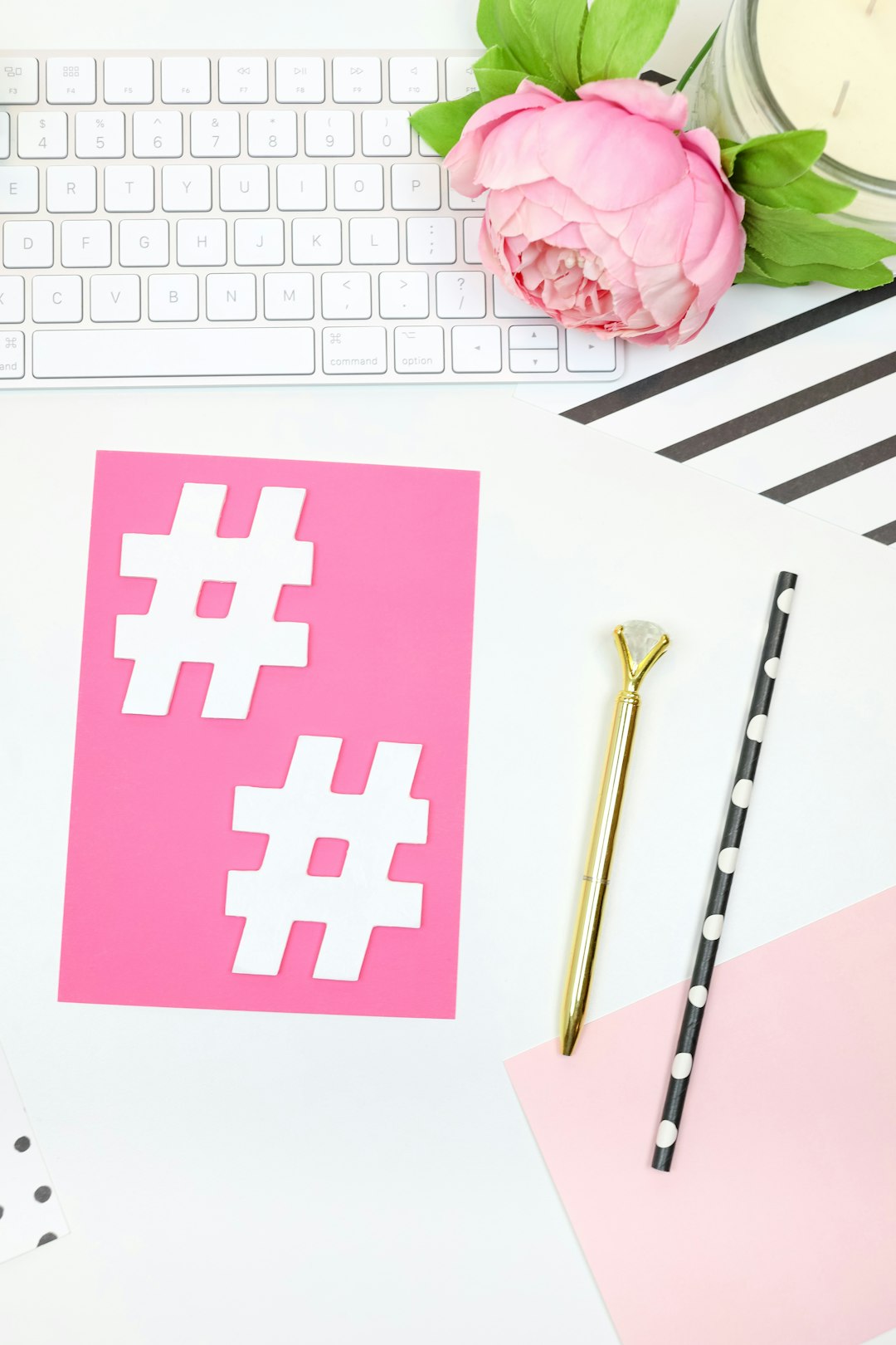 This feminine styled stock photo perfect for lady bosses features hot pink and black props with a white desk, a keyboard, pink and black notecards, pens, hashtags, and more.