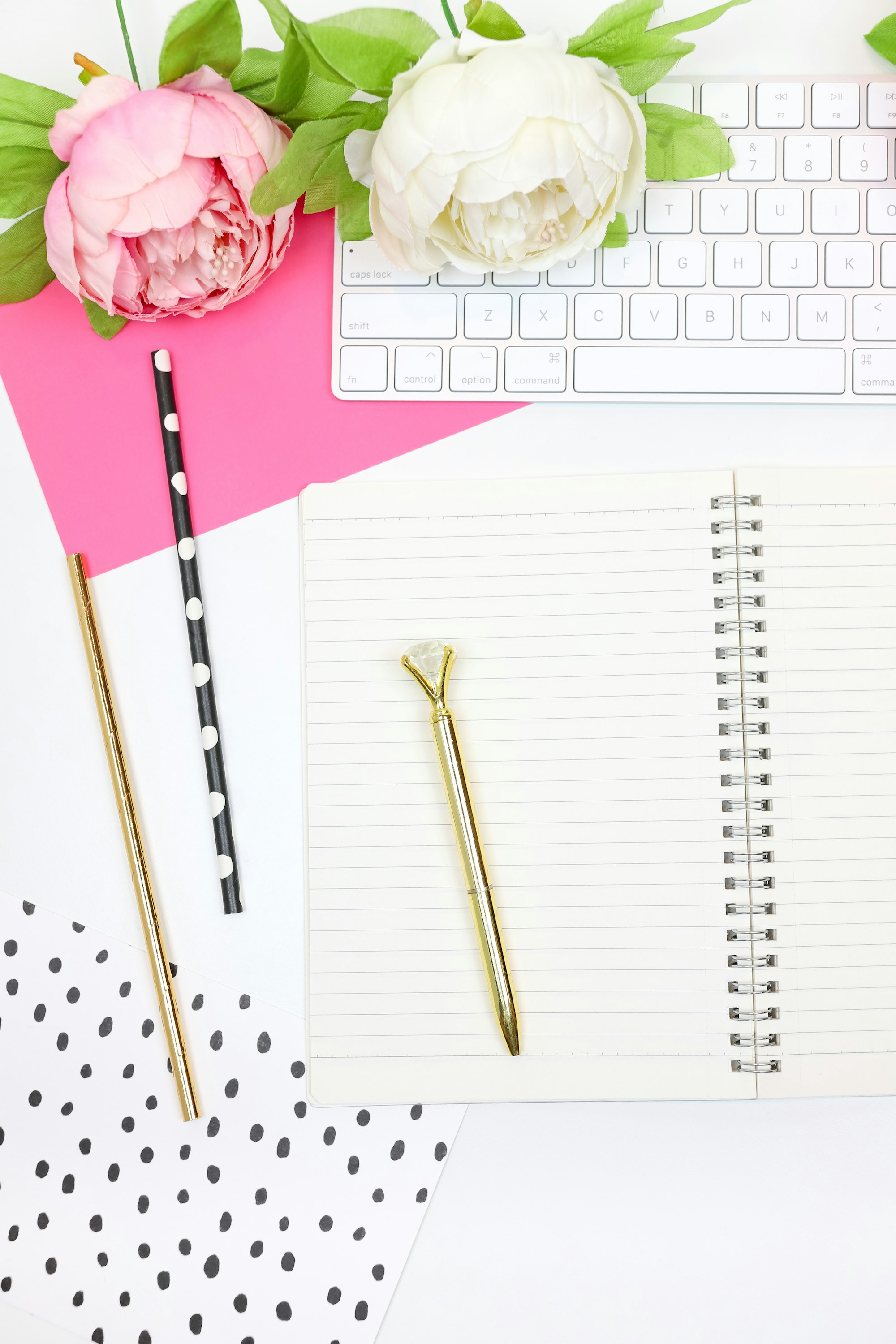 This feminine styled stock photo perfect for lady bosses features hot pink and black props with a white desk, a keyboard, pink and black notecards, pens, a notebook, and more.