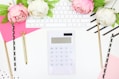 white calculator beside pink rose