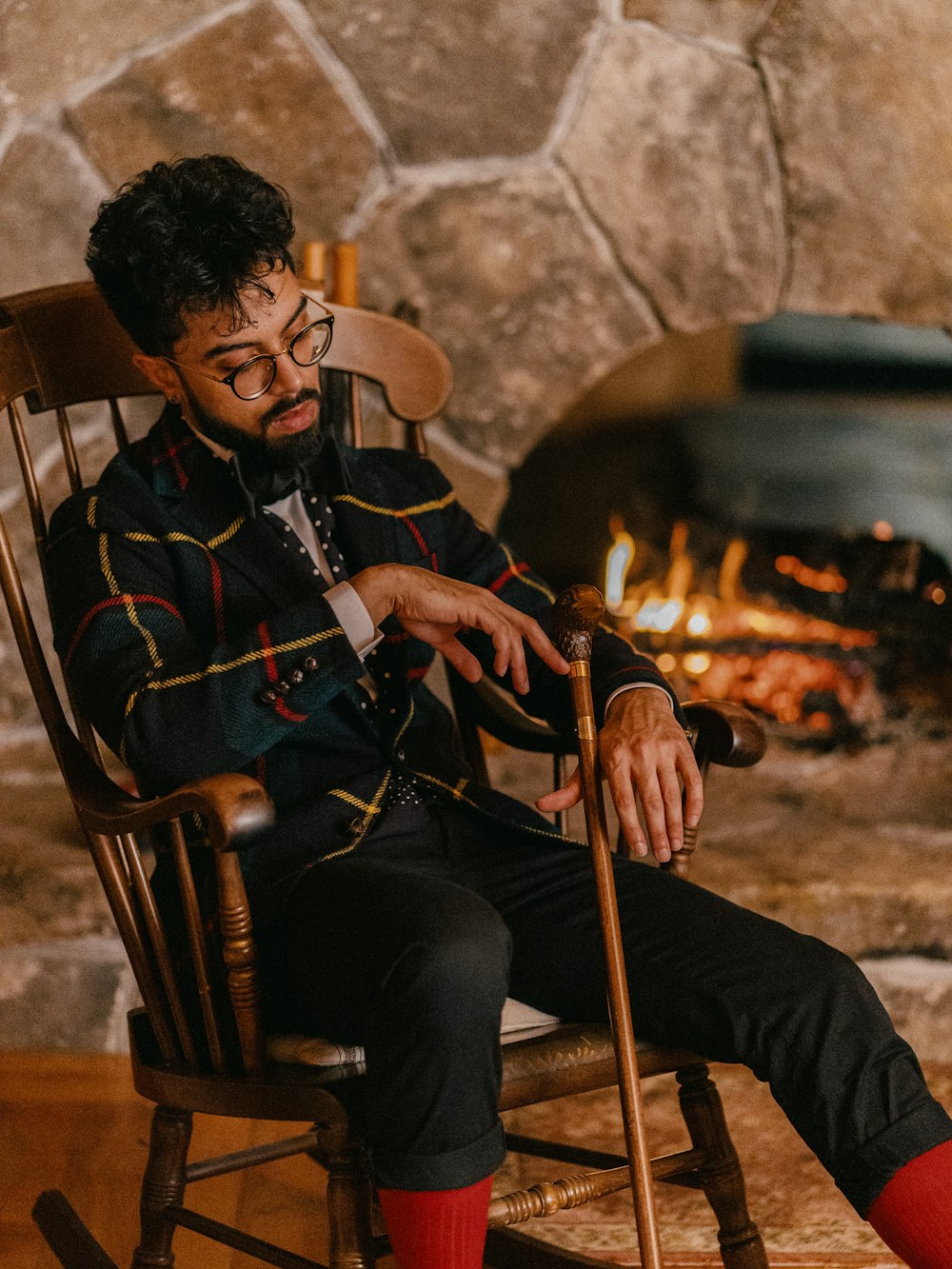 man in black jacket sitting on brown wooden rocking chair