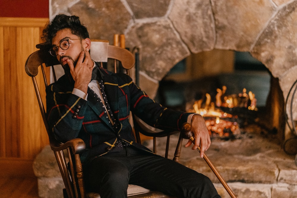 man in black and white long sleeve shirt sitting on brown wooden armchair