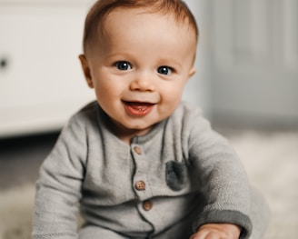 baby in gray sweater lying on white textile