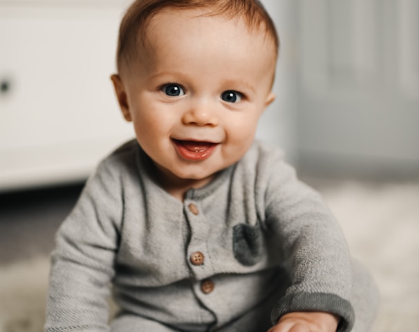 baby in gray sweater lying on white textile