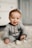 baby in gray sweater lying on white textile