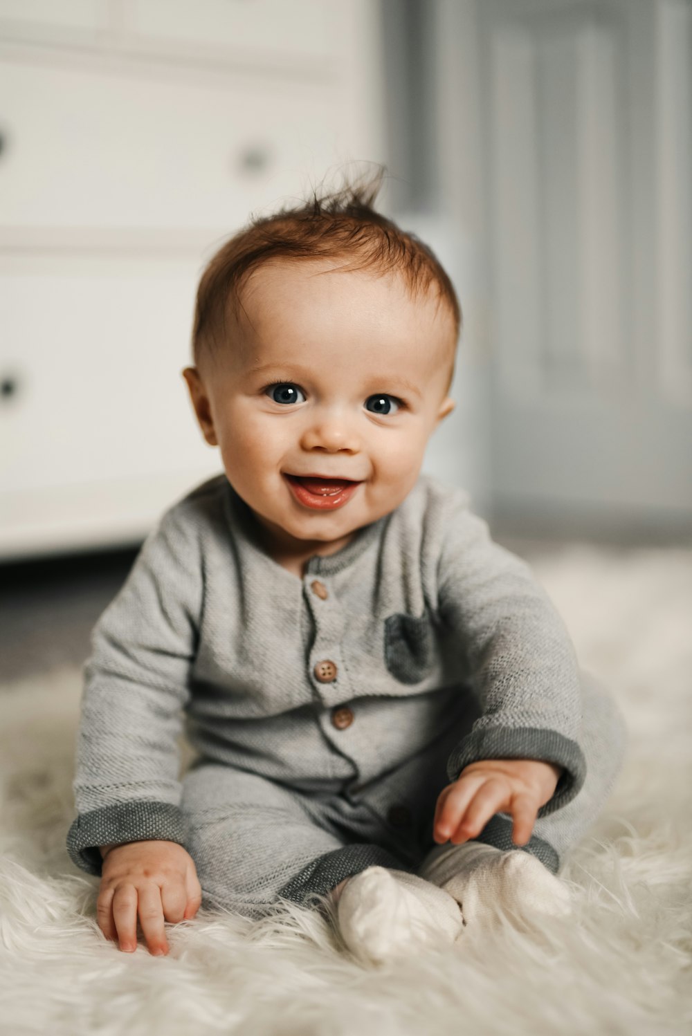 Baby im grauen Pullover auf weißem Textil liegend