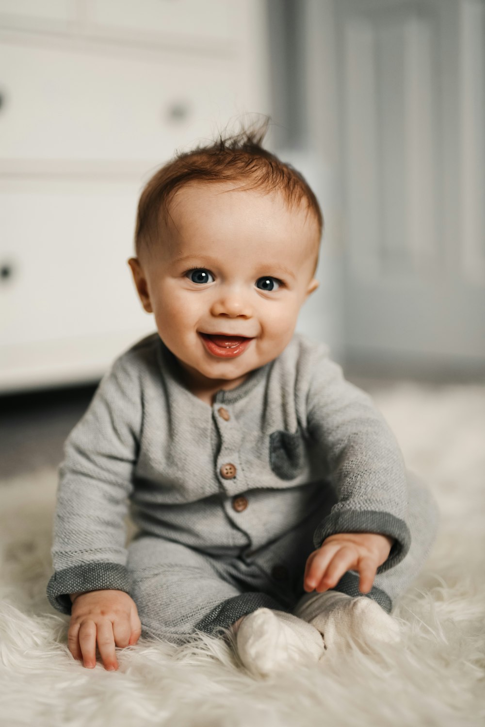 bébé en pull gris couché sur textile blanc