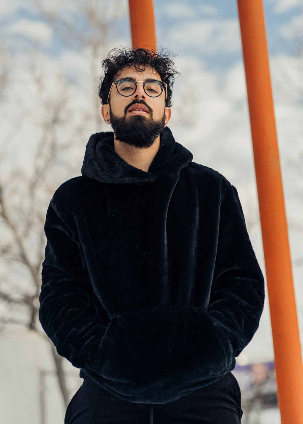 man in black hoodie standing near orange post