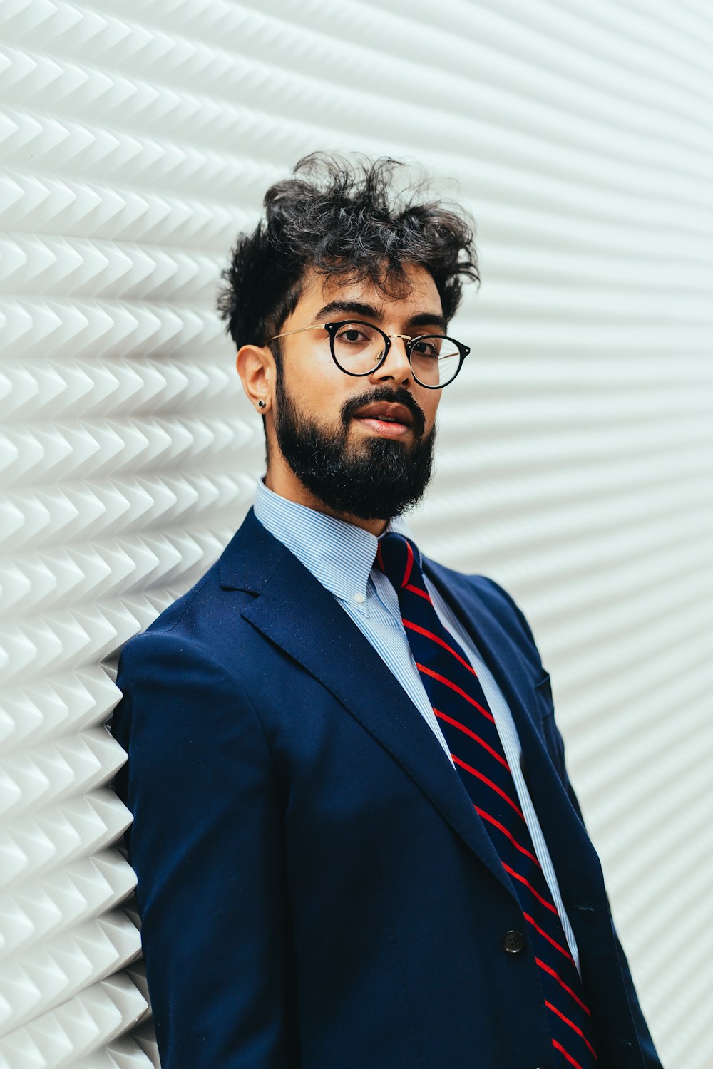 Mann in blauer Anzugjacke mit schwarz gerahmter Brille