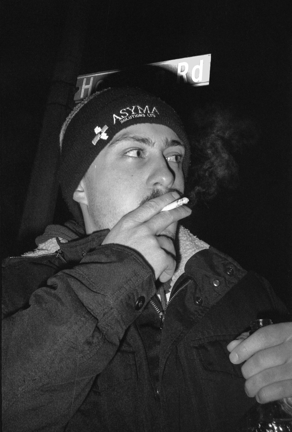 Mann mit schwarzer Mütze raucht Zigarette