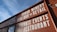 A building facade with bold white lettering on a reddish-brown wall advertising an urban winery, wine bar, restaurant, and space for private events. The text is prominently displayed against the backdrop of a clear blue sky.