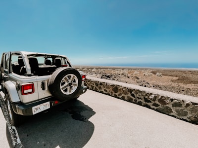 white and black suv on gray sand under blue sky during daytime