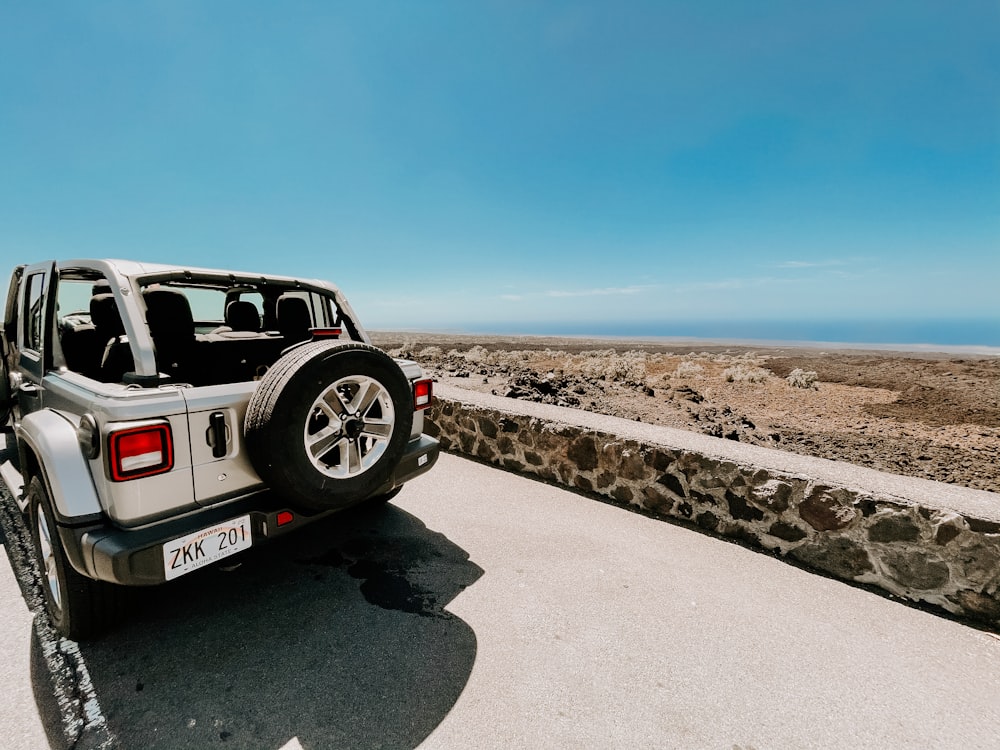 white and black suv on gray sand under blue sky during daytime