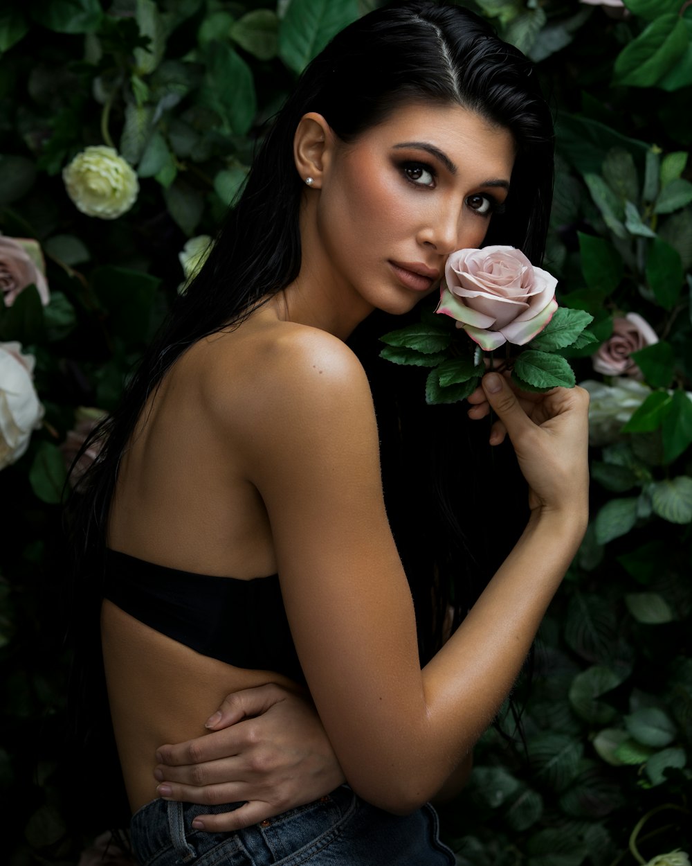 woman in black brassiere holding pink rose