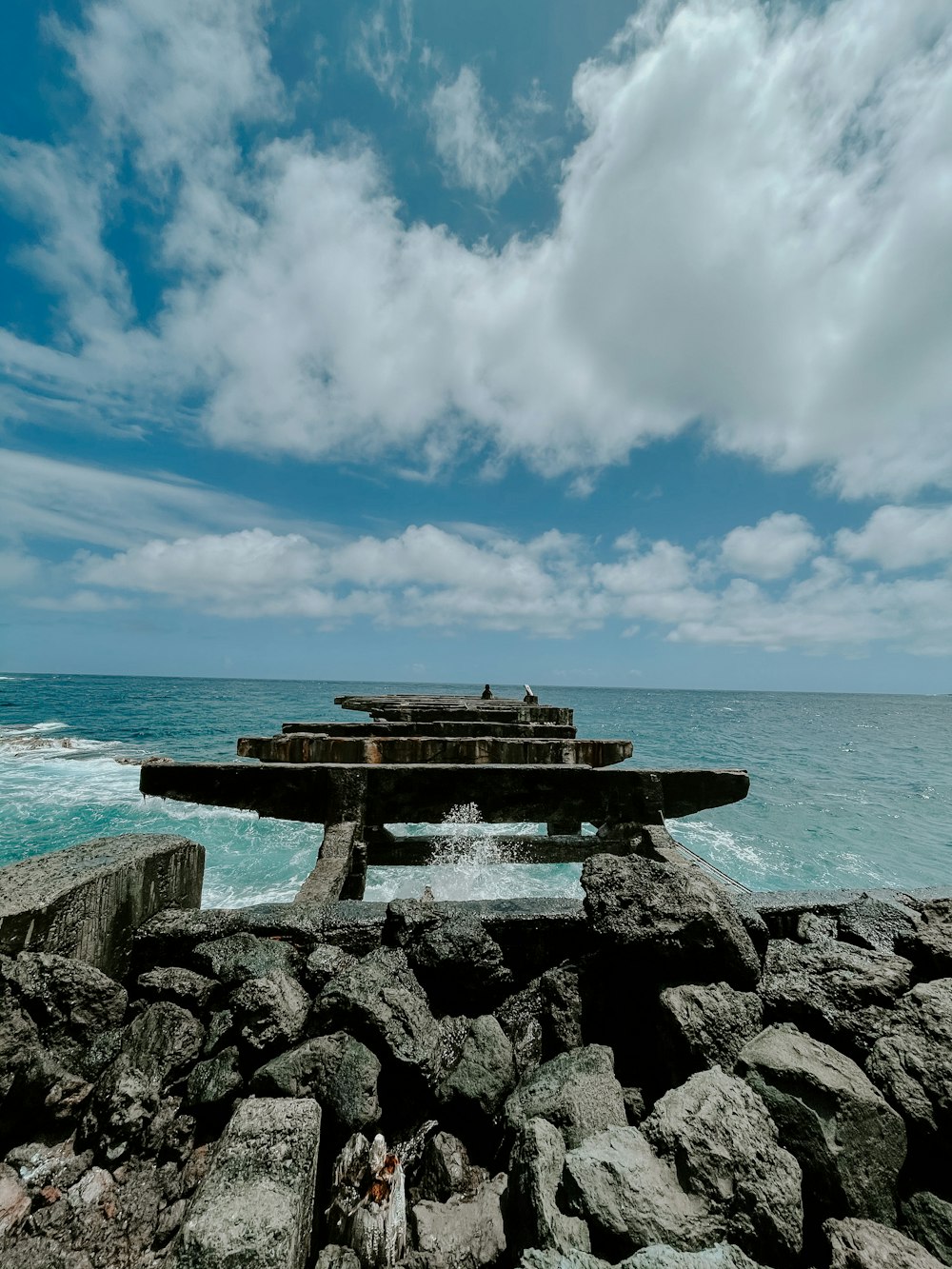 brown wooden bench on gray rock near body of water during daytime