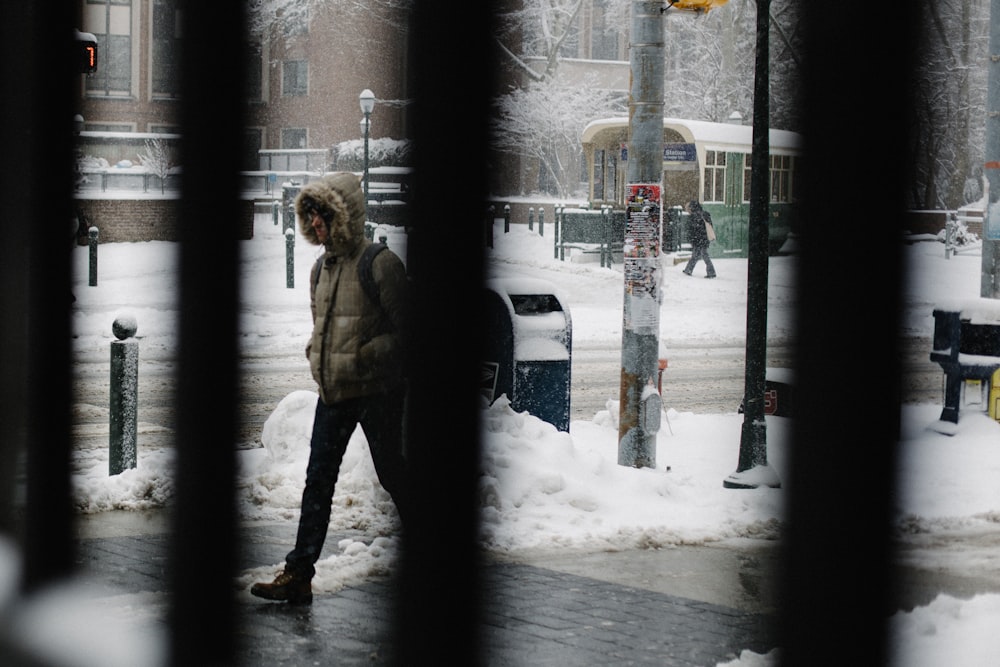 woman in brown coat standing on snow covered ground during daytime