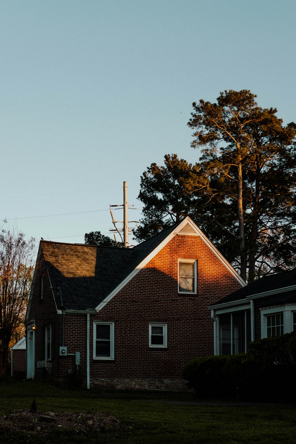 brown and white house beside green tree under gray sky