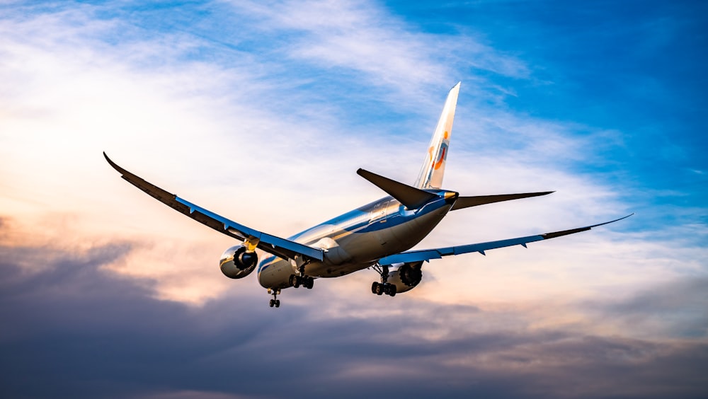 aeroplano blu e bianco che vola durante il giorno