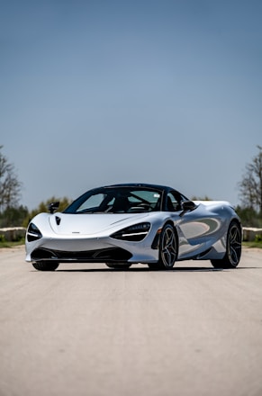 A sleek luxury car parked on a scenic highway under a clear blue sky.