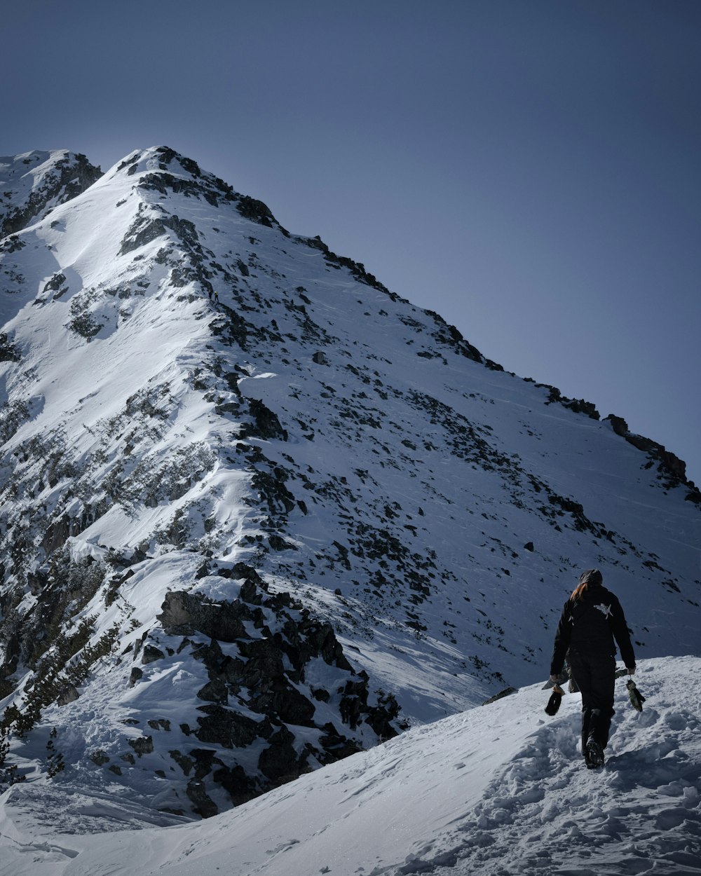 man in black jacket and black pants standing on snow covered mountain during daytime