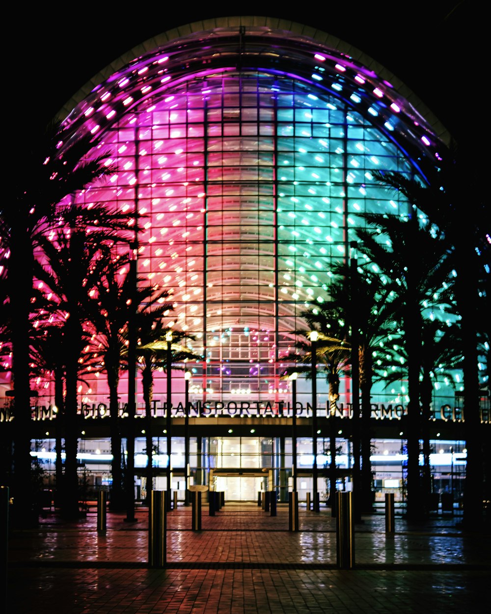 a brightly lit building with palm trees in front of it