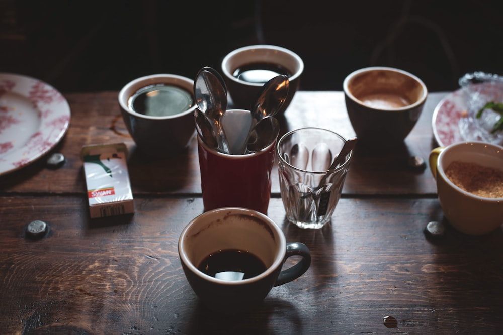 a wooden table topped with cups of coffee